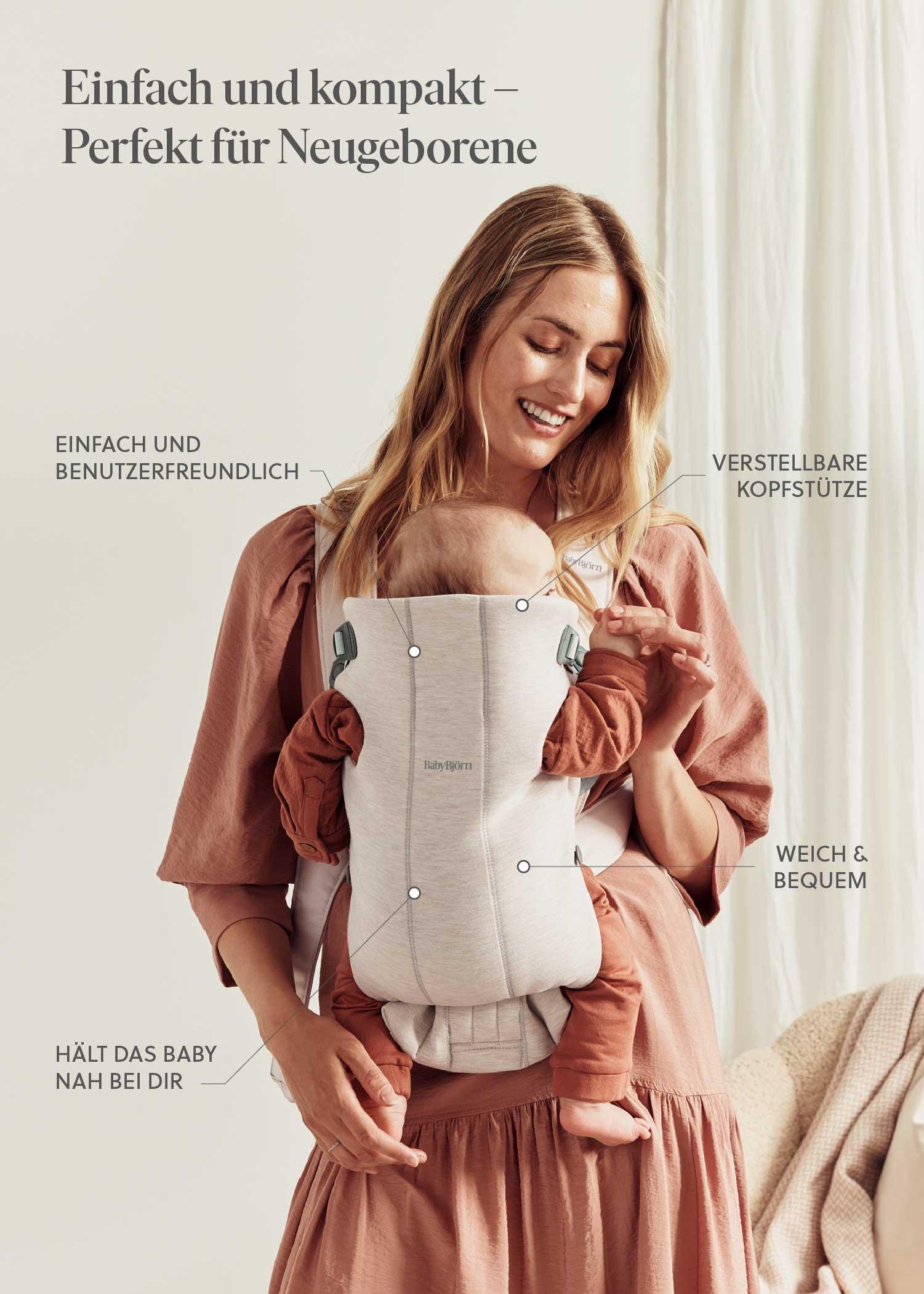 A woman with long hair smiles while holding a baby in a gray carrier. Text highlights features like adjustability and comfort in German.